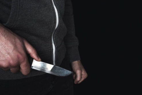 man with a knife in hand close-up with place for text on black background